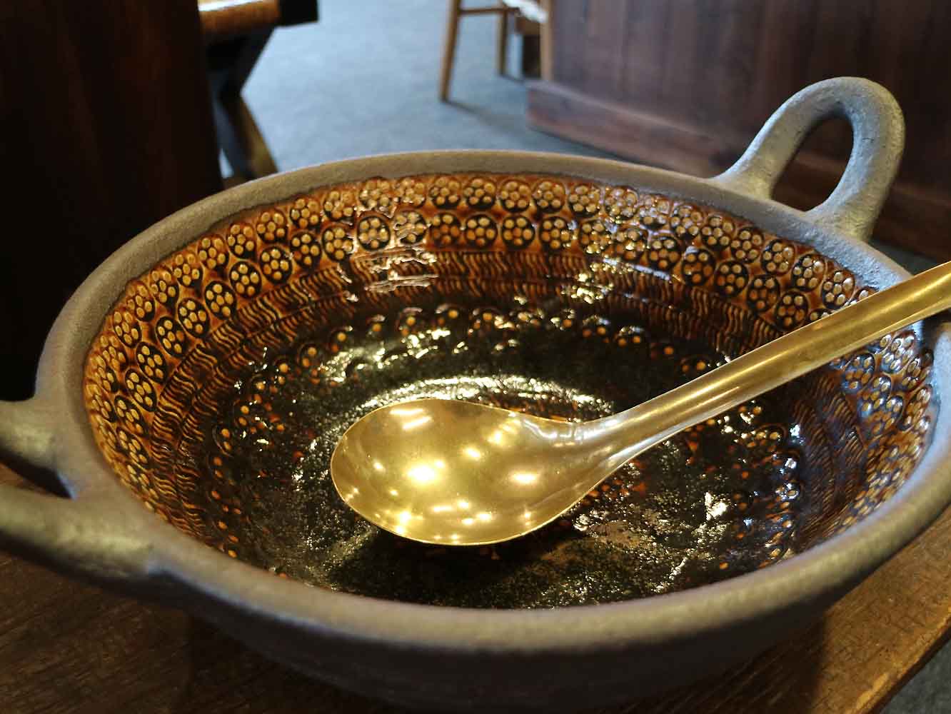 大きな押紋土鍋は、鳥取県「岩井窯」の山本教行さんの作品。真鍮のおたまは岡山県の菊地流架さん作